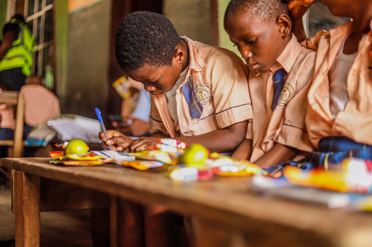 Young students focused on writing and studying together in a classroom environment.